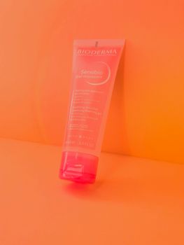 Close-up of Bioderma Sensibio gel against a vibrant orange backdrop.