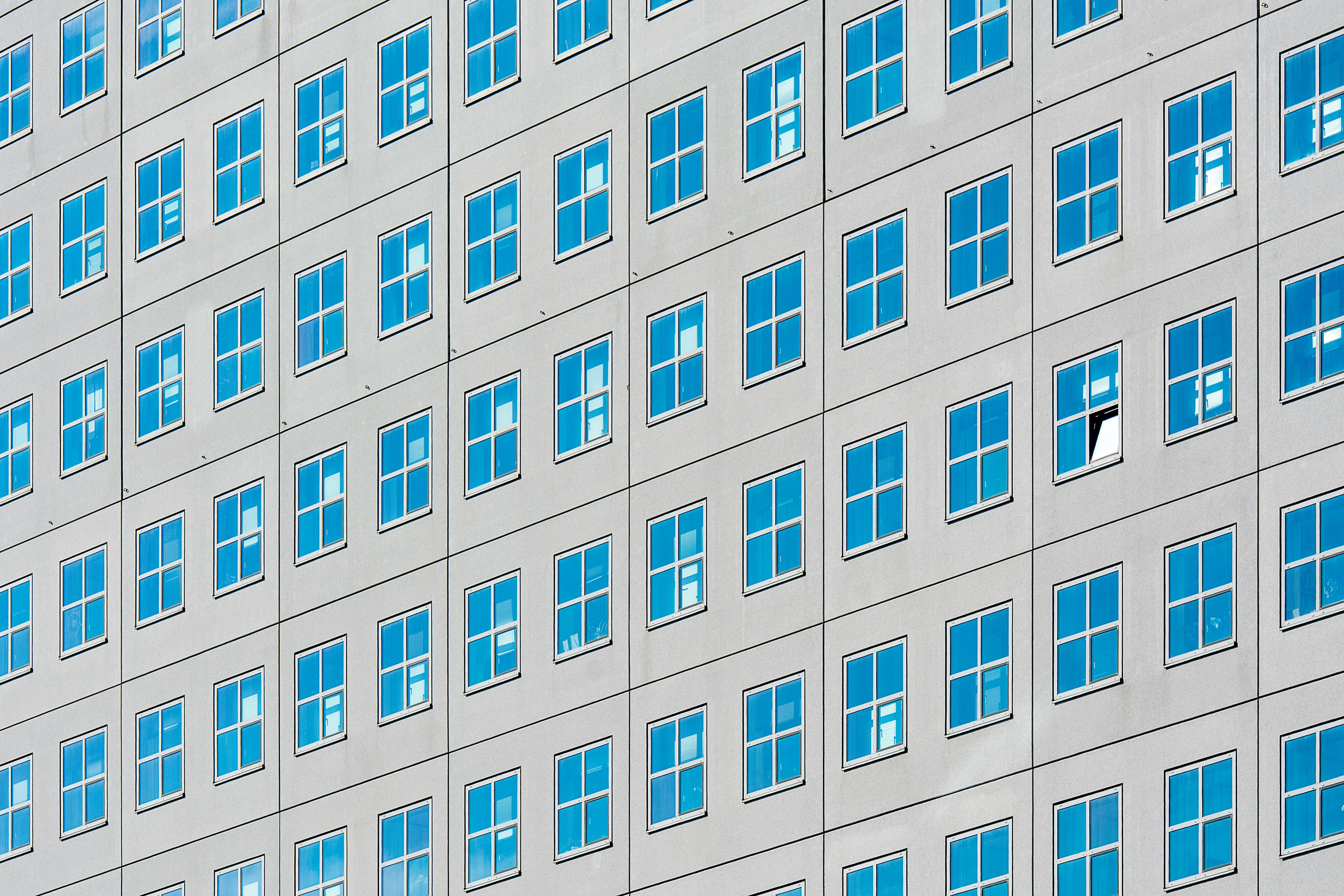 A building facade showcasing a geometric pattern of square windows reflecting the sky.