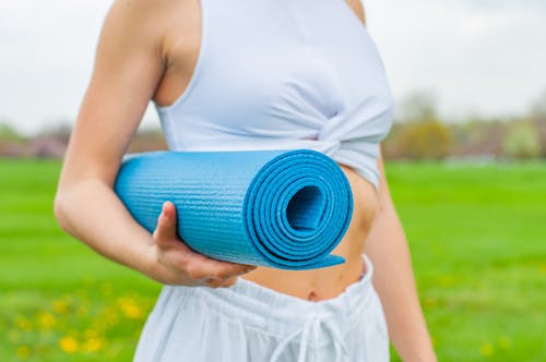 Free Woman Standing and  Holding Blue Yoga Mat Stock Photo