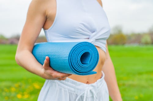 Mulher Em Pé Segurando Um Tapete De Ioga Azul