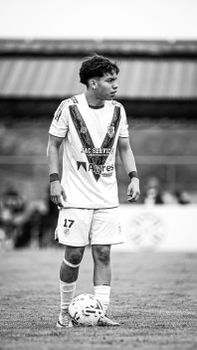 Black and white photo of a soccer player in action during a match.