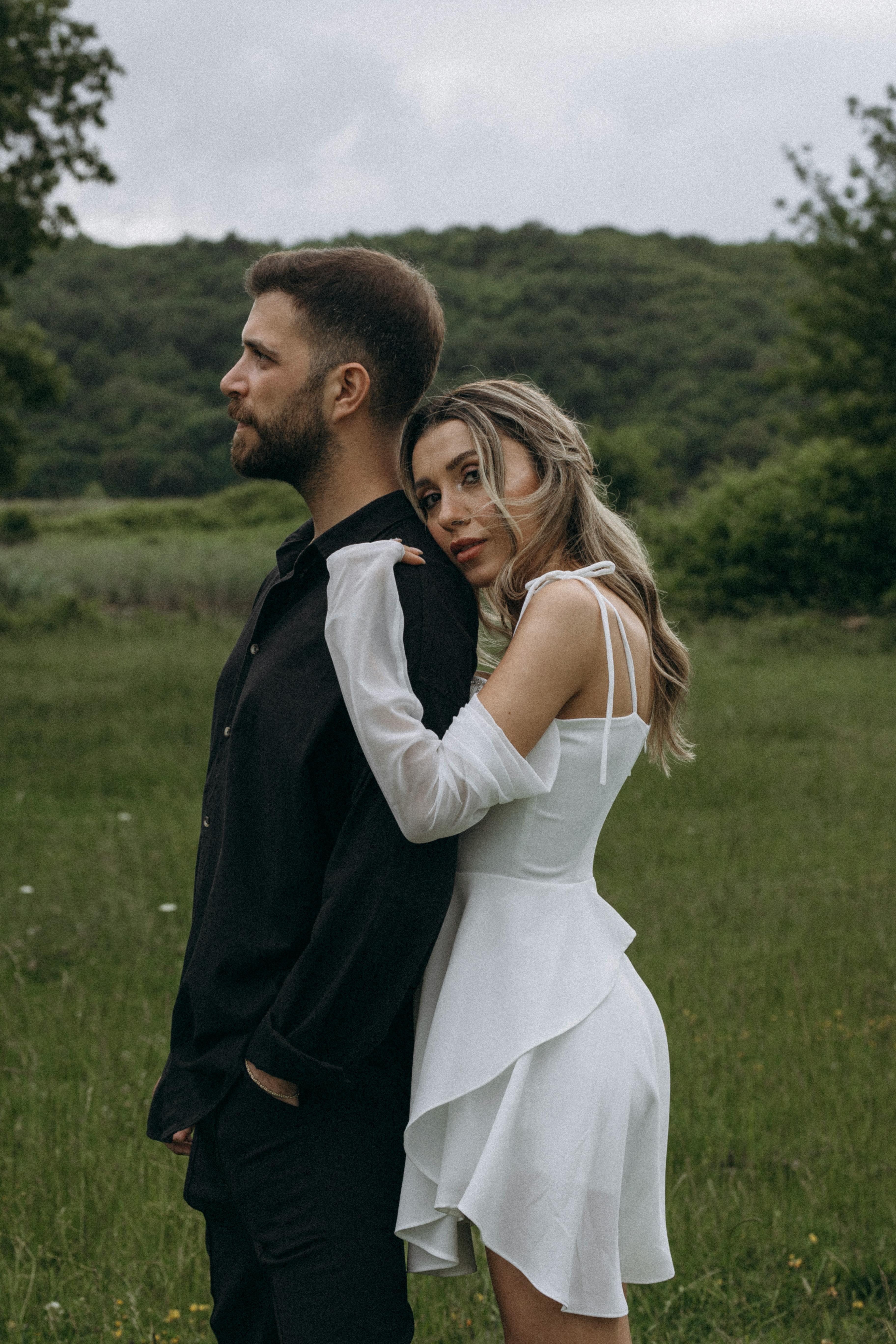 Romantic outdoor portrait of a stylish couple embracing in a serene green meadow.