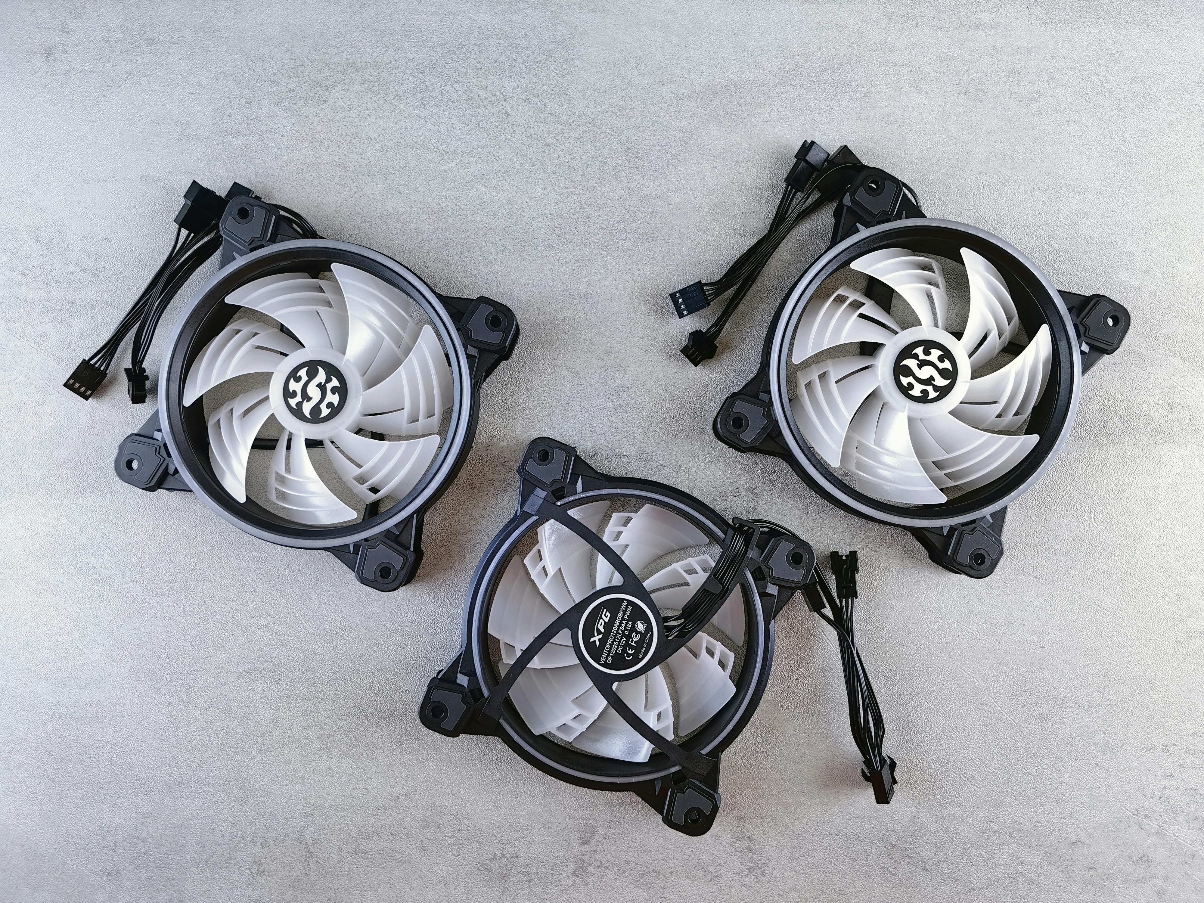 Flat lay of three computer cooling fans with cables on a light gray background for tech and electronics themes.