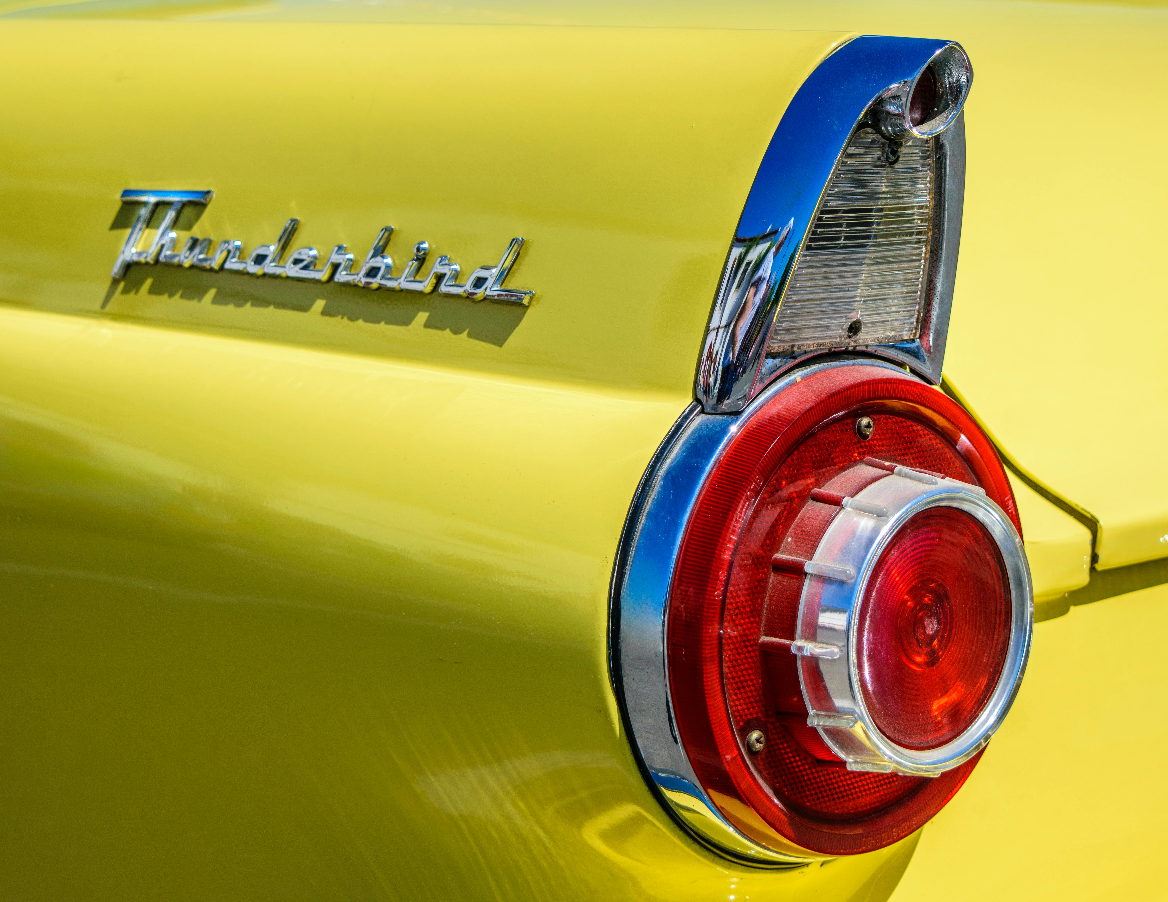 Bright yellow Ford Thunderbird showcasing classic vintage design with a close-up of the taillight.