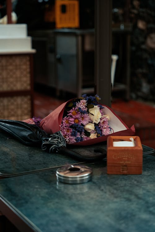 A bouquet of flowers sits on a table next to a box