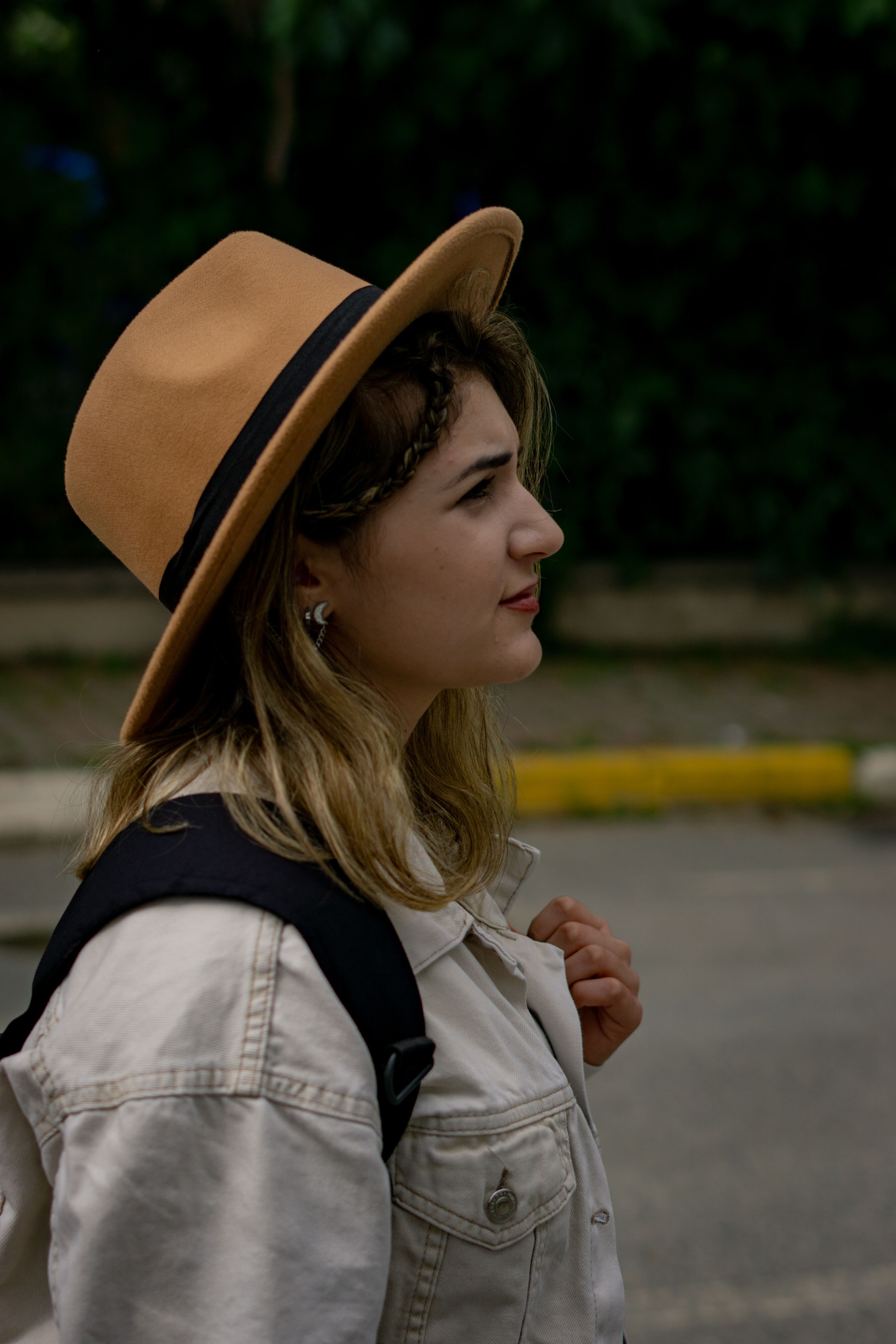 Mulher estilosa usando um chapéu e mochila posa ao ar livre, mostrando moda casual.