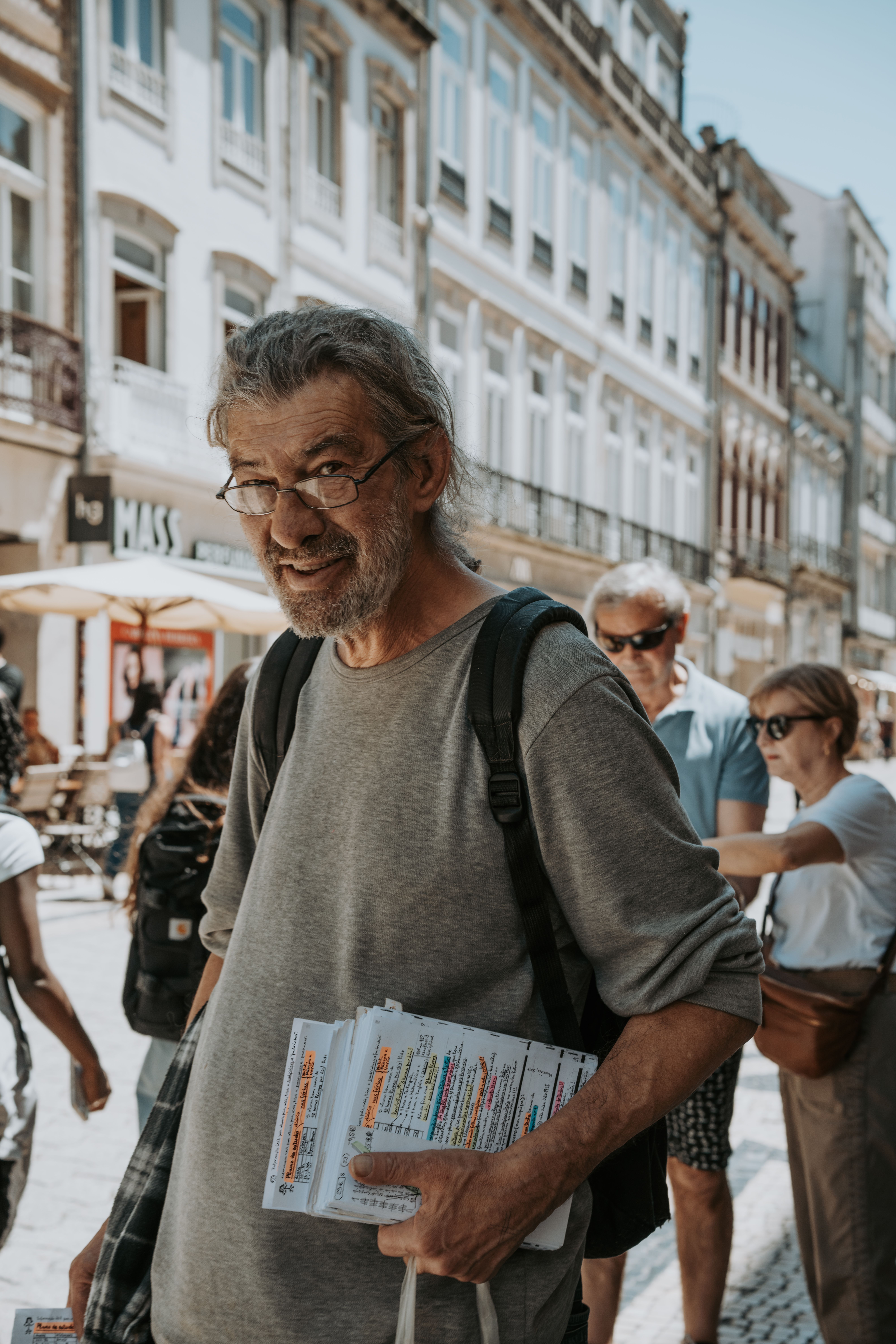 Elderly man with eyeglasses holding a map on the streets of Porto, Portugal.