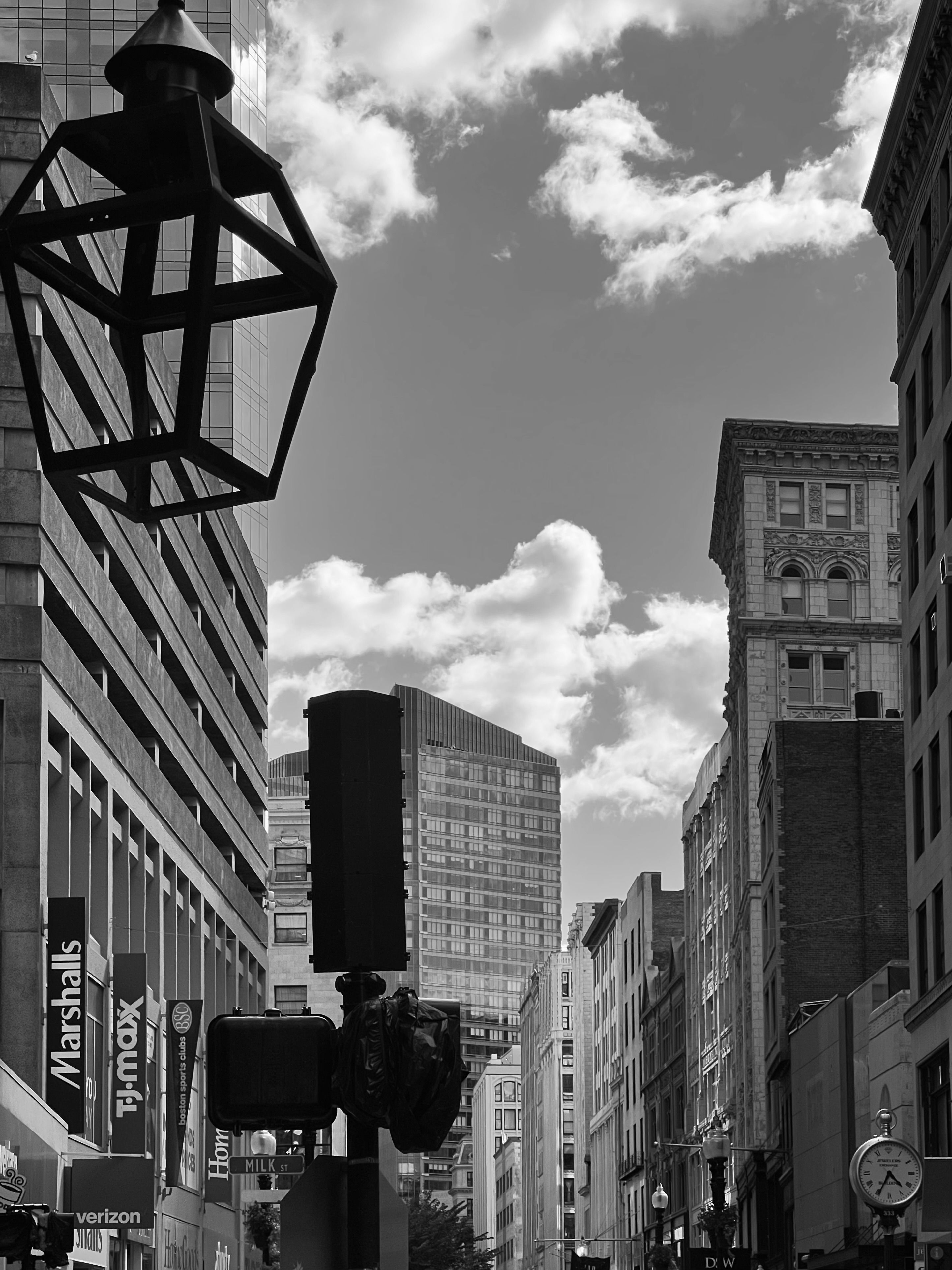 Dynamic black and white street view of a bustling urban cityscape with skyscrapers under a cloudy sky.