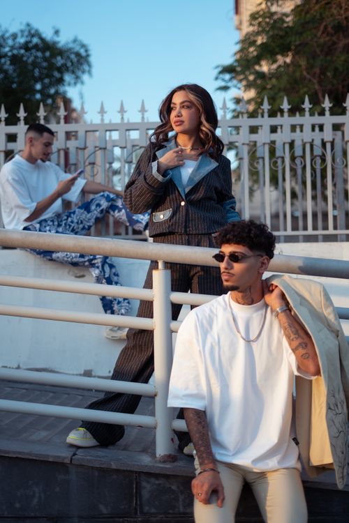 Free Trendy young adults pose with a fence backdrop in Baghdad, highlighting urban fashion. Stock Photo