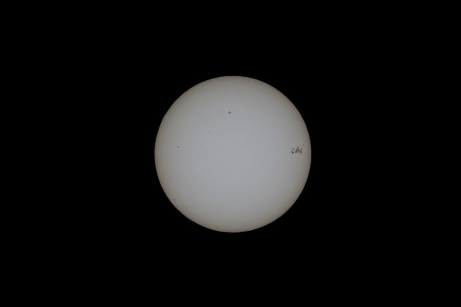 Close-up image of the sun with visible sunspots on a black background.