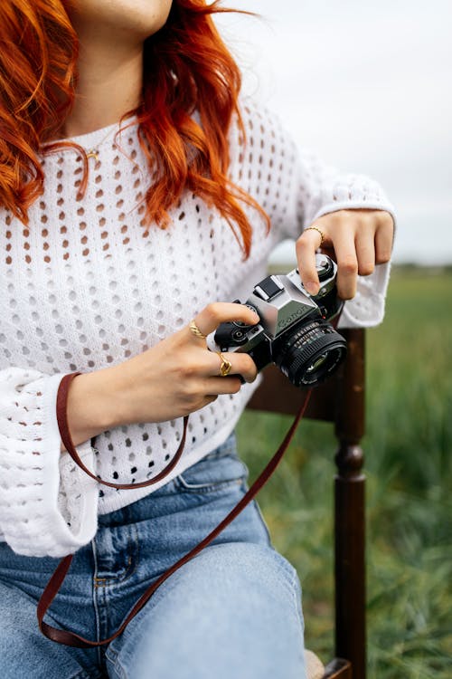 A woman with red hair holding a camera