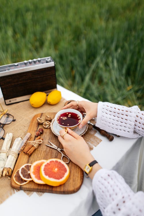 A woman is sitting on a picnic table with a cup of tea