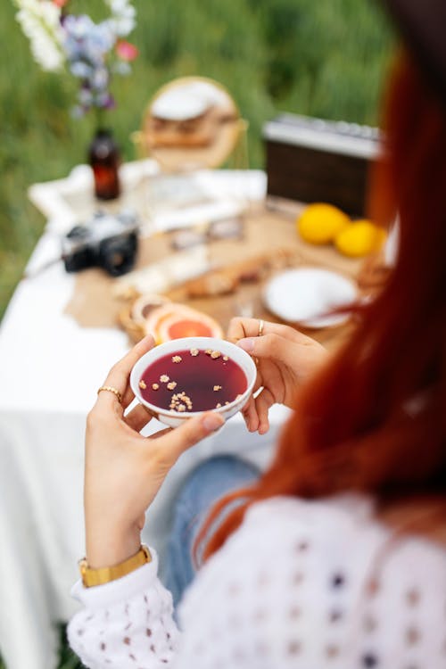 A woman holding a cup of tea and a plate of food