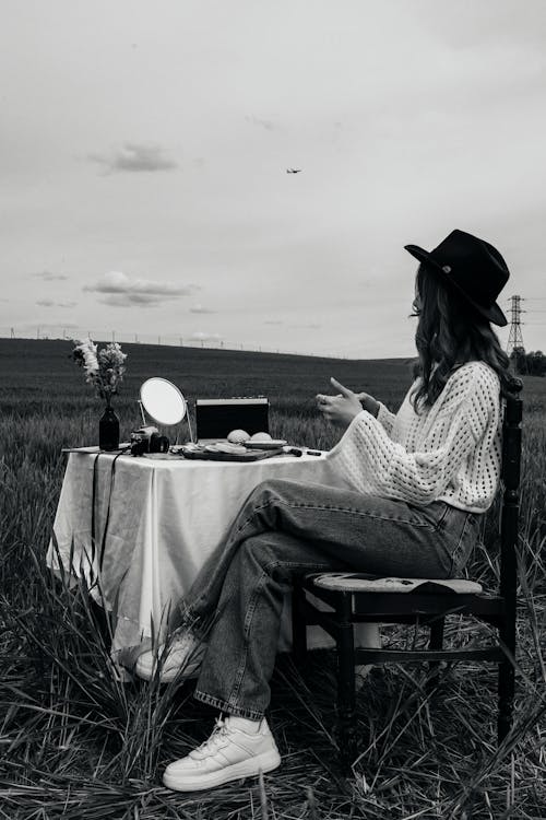 A woman sitting in a field with a hat on