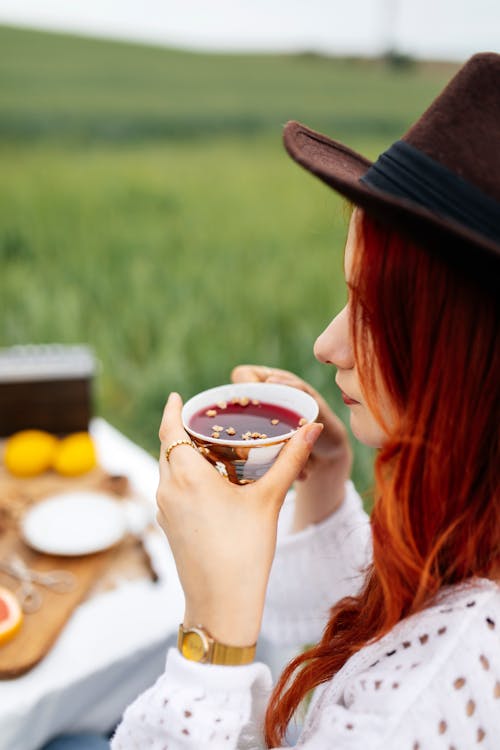 A woman drinking tea in a hat and a straw
