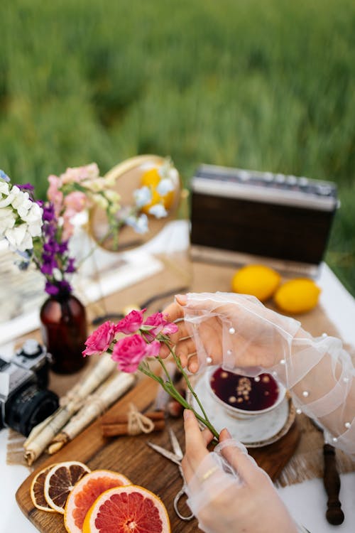 A woman is holding a flower and a cup of tea