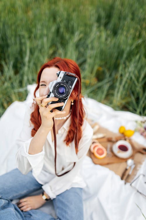 A woman with red hair taking a photo with her camera