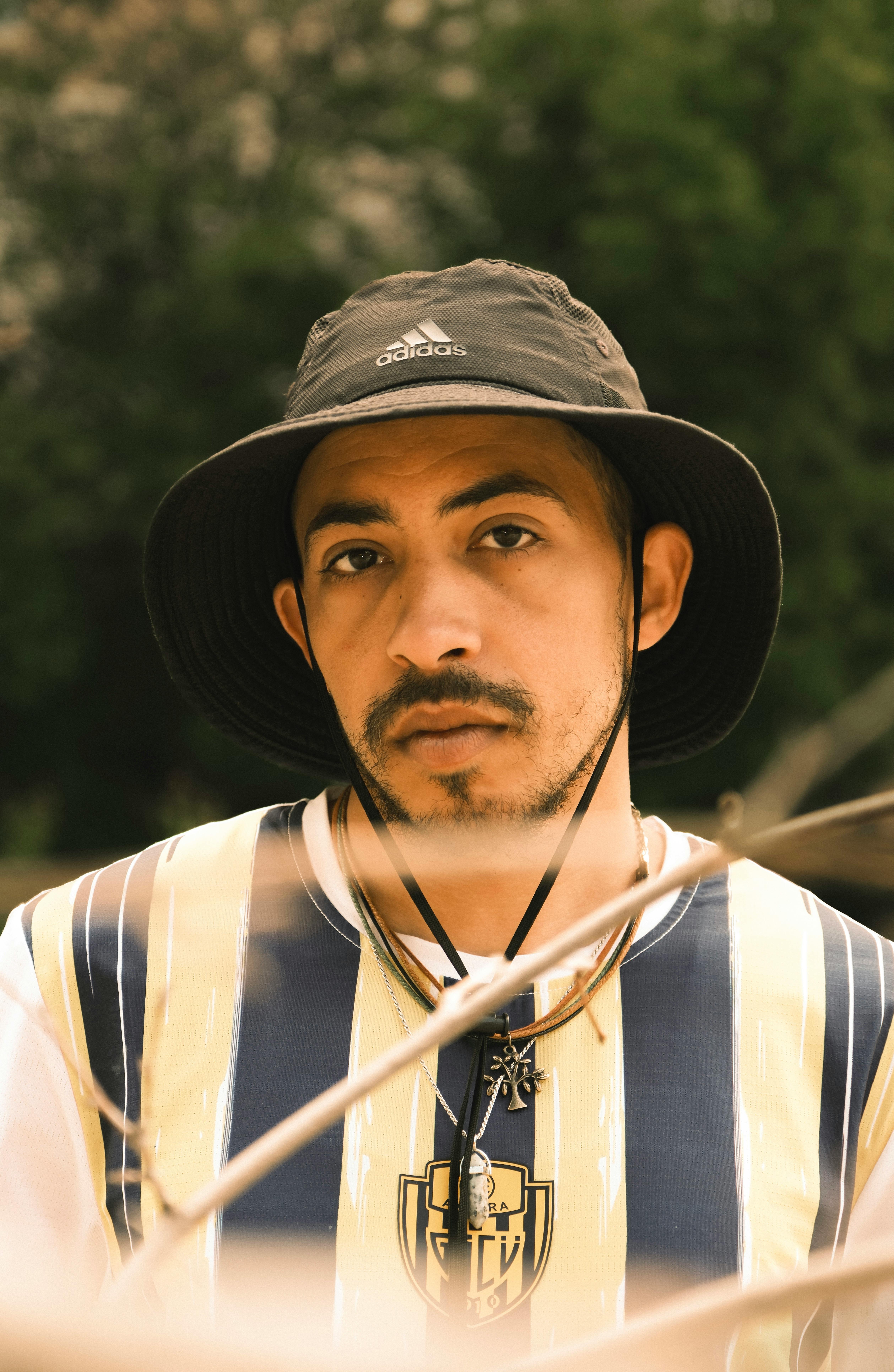 Portrait of a man wearing a hat and jersey, posing outdoors in Ankara, Türkiye.