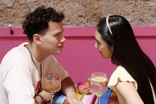 Free A young couple shares a moment over drinks at a vibrant cafe setting. Stock Photo
