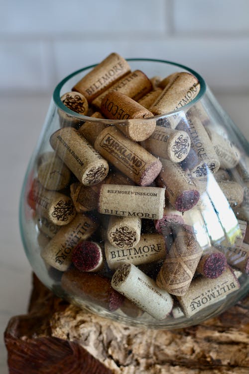 A glass jar filled with wine corks on a log