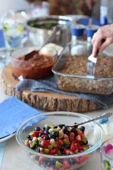 Hand preparing a meal with fresh fruit salad, perfect for lively gatherings.