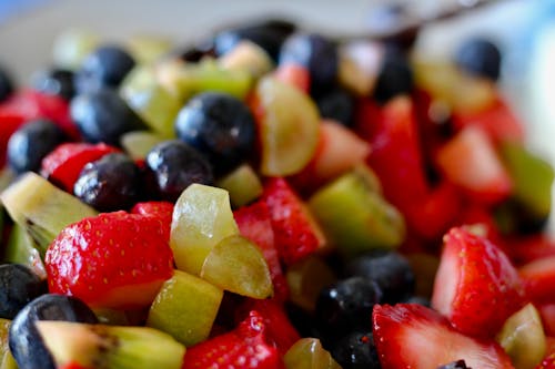 A plate of fruit salad with blueberries, strawberries and grapes
