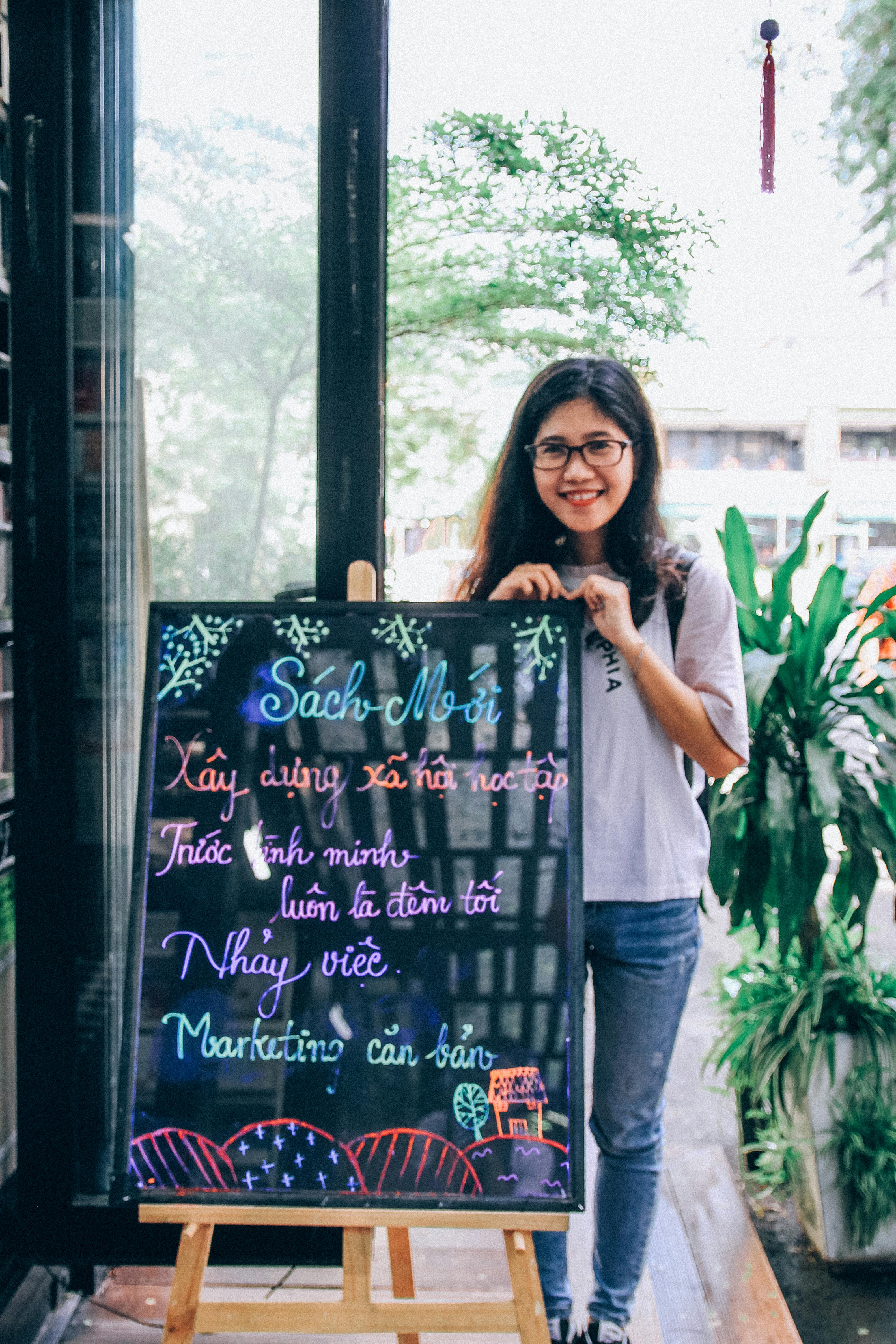 Woman Wearing Blue Jeans Holding On Menu Board Free Stock Photo