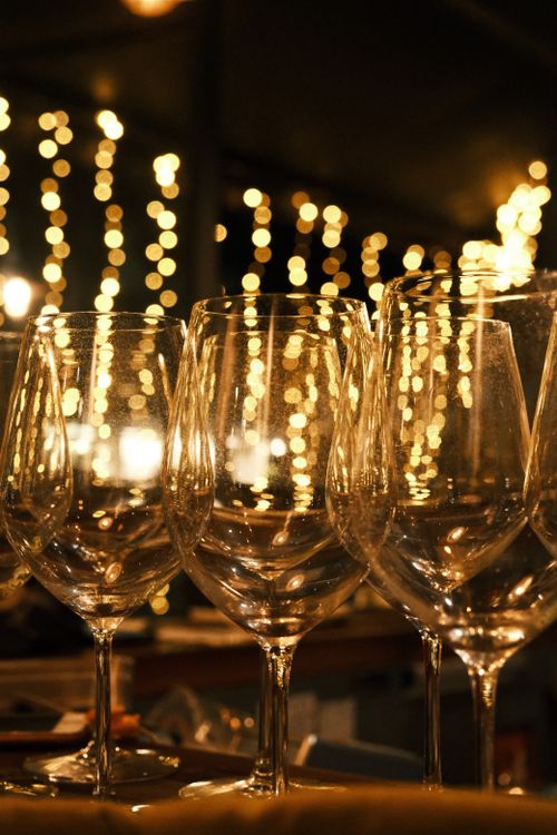 Free A beautiful arrangement of empty wine glasses set against romantic bokeh lights. Stock Photo