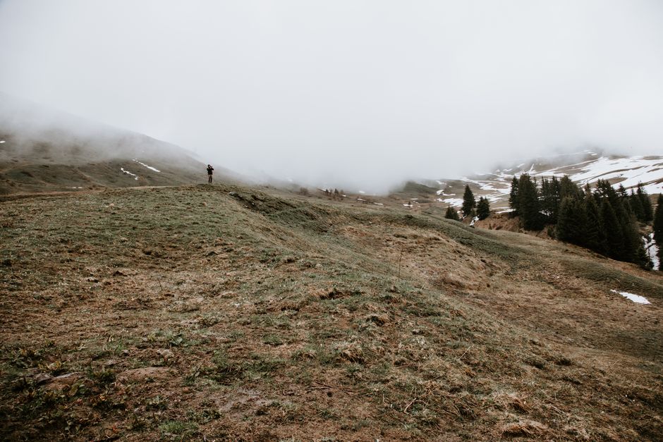 A lone figure stands atop a foggy mountain in Le Grand-Bornand, France.