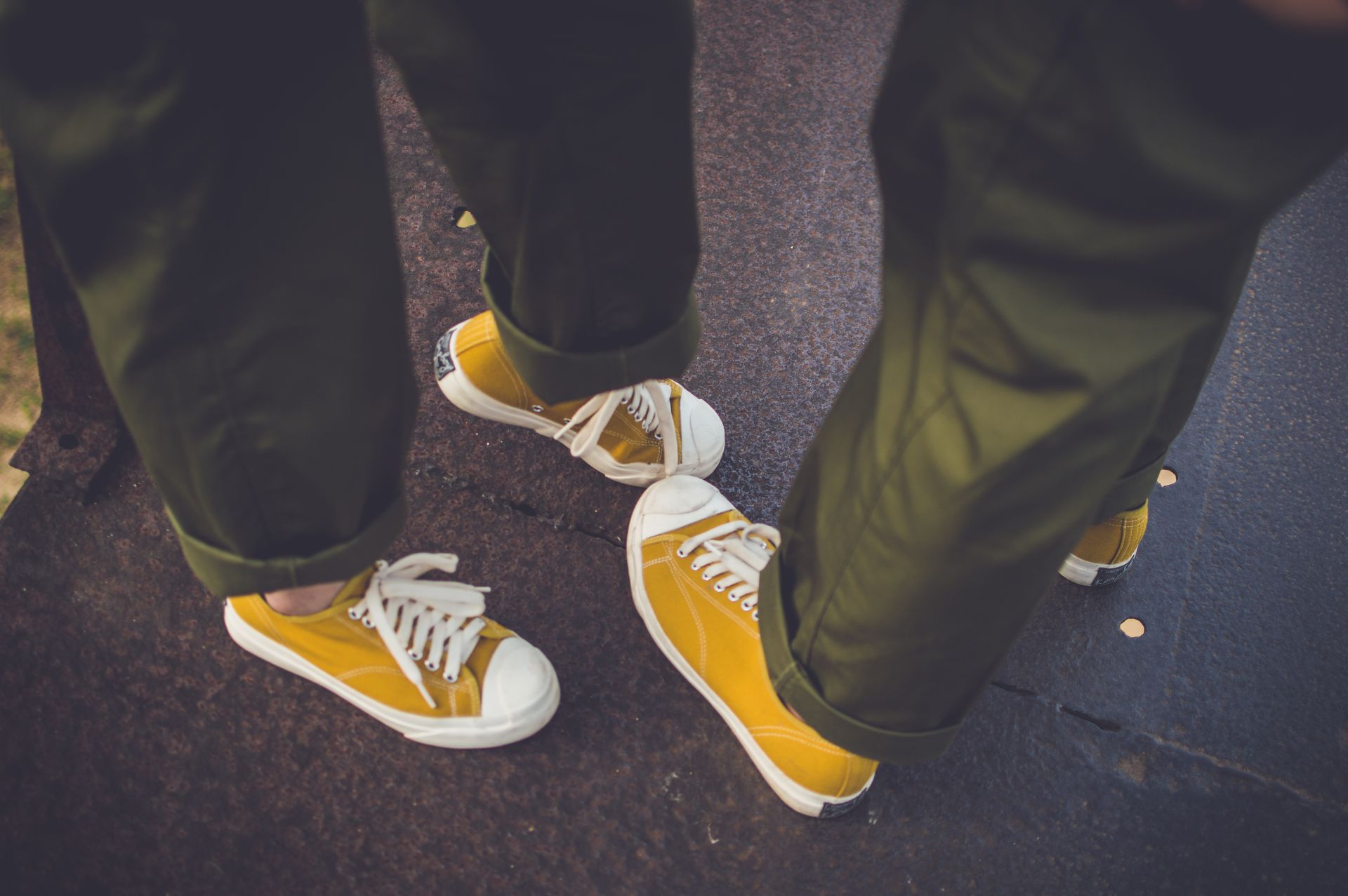 Close-up of two people wearing yellow sneakers standing outdoors, showcasing casual style.
