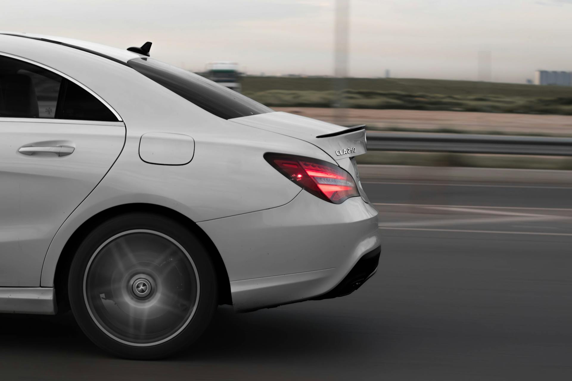 A dynamic shot of a white Mercedes CLA 250 speeding down a highway, showcasing sleek design and motion blur.