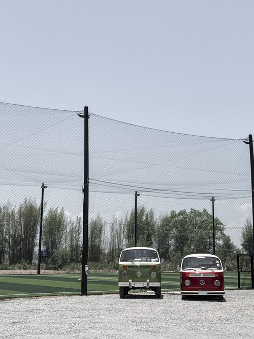 Free Two vintage Volkswagen vans parked near a soccer field in Chiang Mai, Thailand under a clear sky. Stock Photo