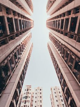 Low angle shot of urban residential skyscrapers forming a symmetrical perspective against the sky.