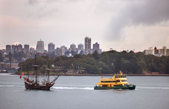 A modern ferry and vintage ship in Sydney Harbour with cityscape backdrop.