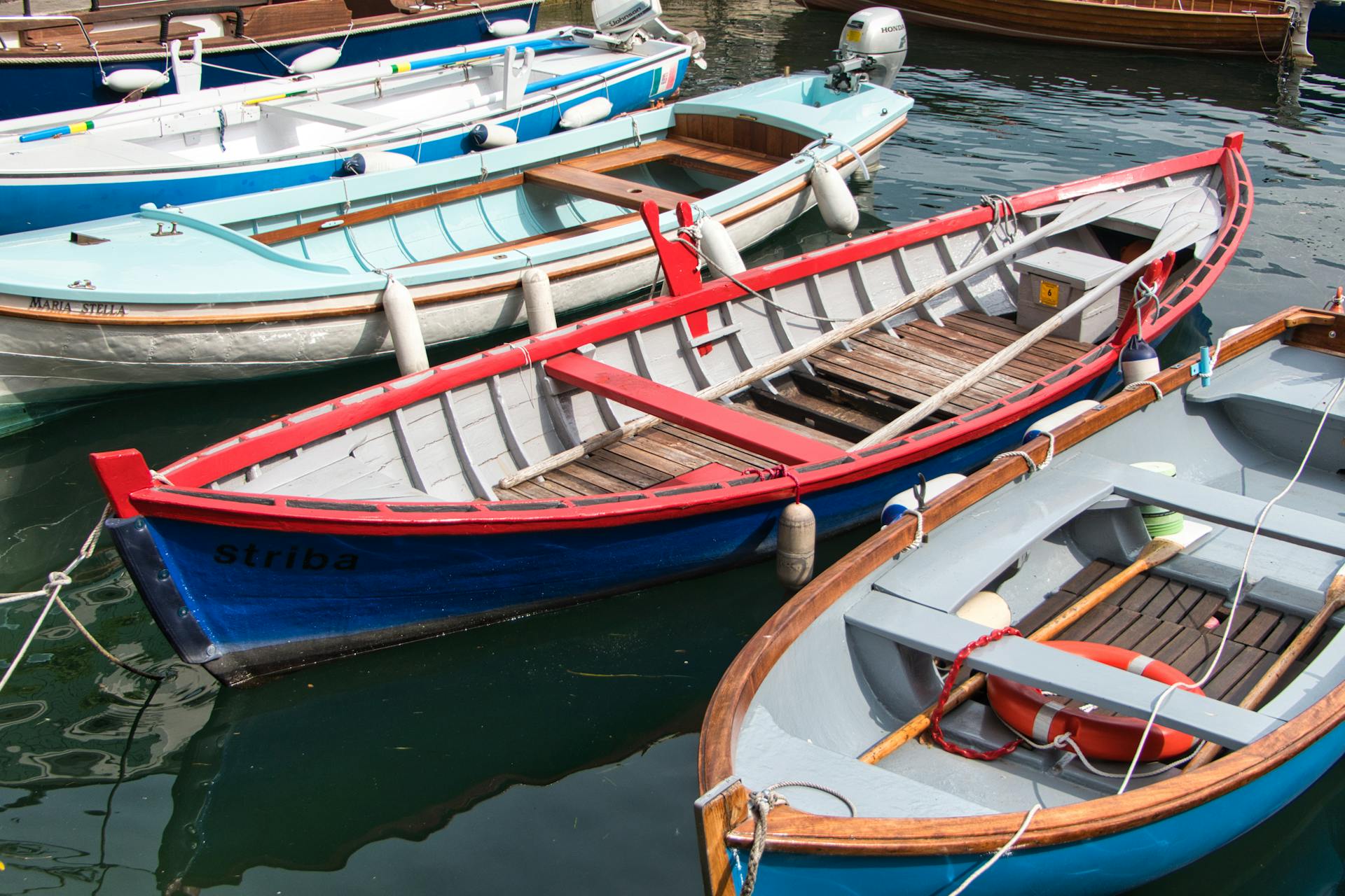 Vibrant wooden boats docked in Malcesine, Veneto, Italy, on a sunny day.