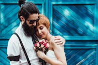 一对夫妇在蓝色门前手捧花束相拥的迷人时刻，非常适合订婚或婚礼主题