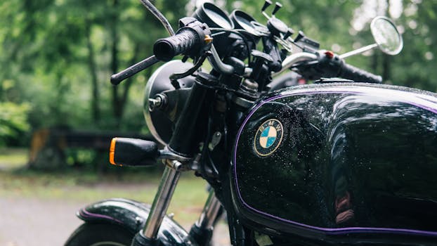 雨滴点缀的森林道路上，一辆经典摩托车的特写，优雅地展现了其复古设计