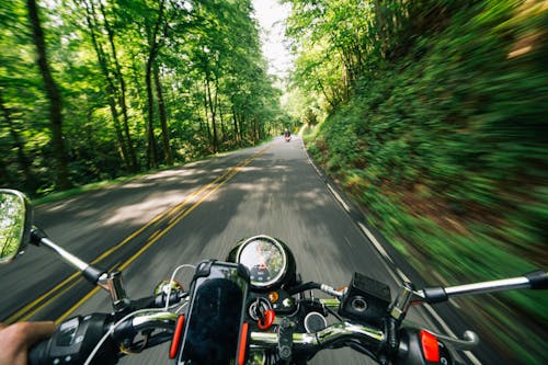 Photo of Person Riding Motorcycle on Road Between Trees