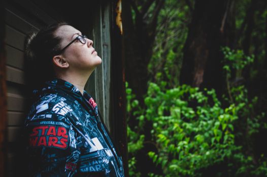 一个女人穿着星球大战夹克，站在户外的绿色植物中