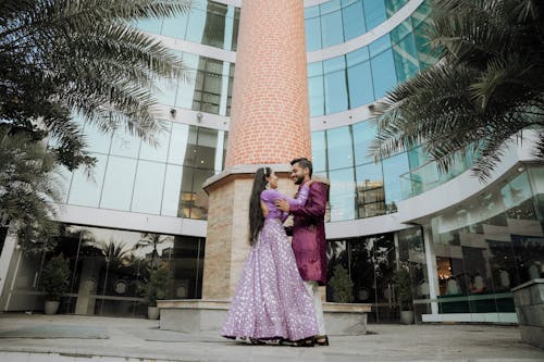 A couple in purple wedding attire standing in front of a building
