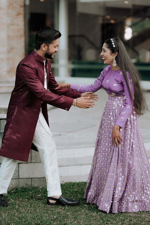 A man and woman in purple outfits shaking hands