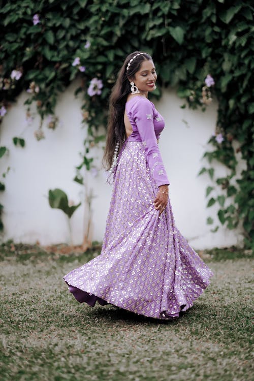 A woman in a purple dress standing in front of a wall