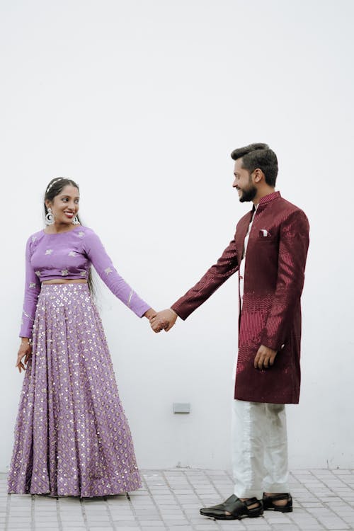 A man and woman holding hands in front of a white wall