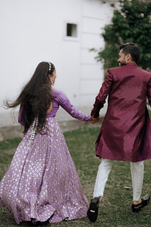 A man and woman in purple outfits holding hands