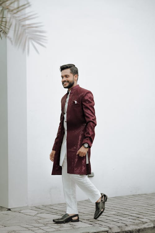 A man in a maroon sherwani and white pants