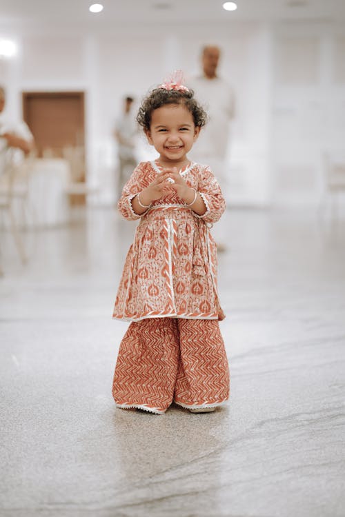 A little girl in a pink dress and orange pants