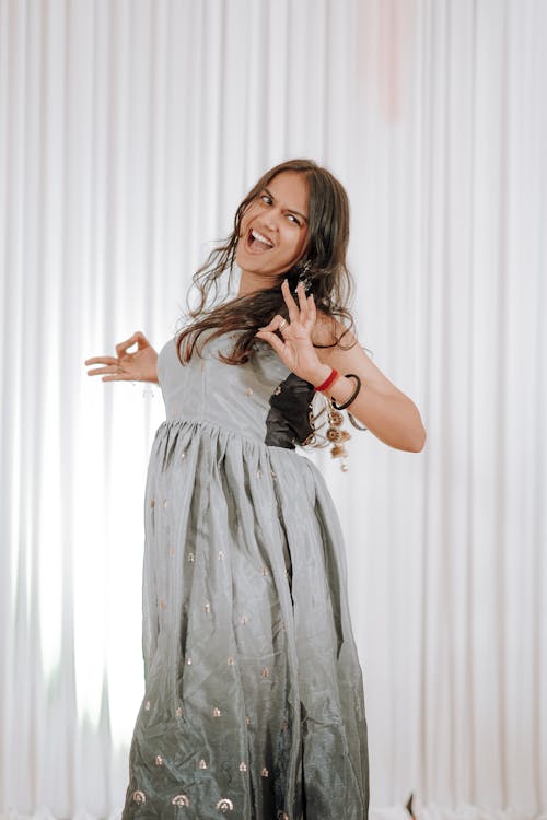 A woman in a long dress is posing for the camera