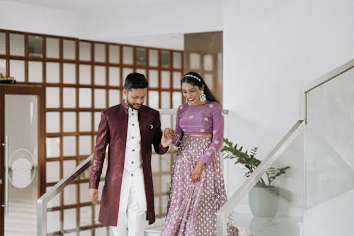 A man and woman in traditional indian attire walking down the stairs