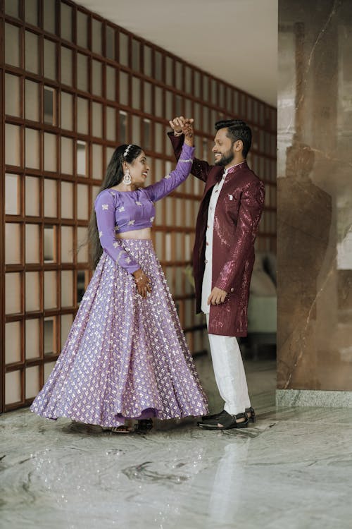 A couple in traditional attire standing in front of a wall