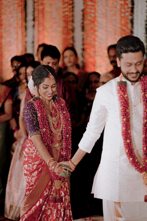 A man and woman in traditional indian attire walking down the aisle